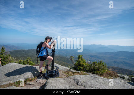 Mujer mirando a través de binoculares en la cumbre de la montaña Whiteface Foto de stock