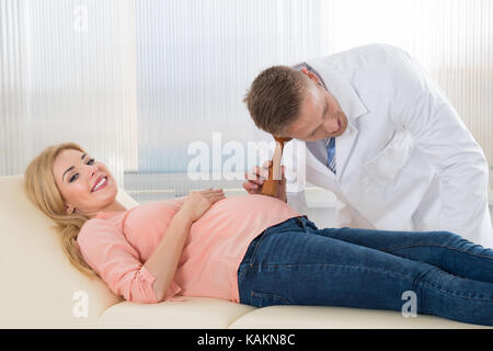 La mujer embarazada escucha los latidos del corazón y los movimientos del  bebé con un estetoscopio o un fetoscopio o un Pinard Horn. Salud fetal  prenatal, ansiedad, concepto del miedo. Fotografías de