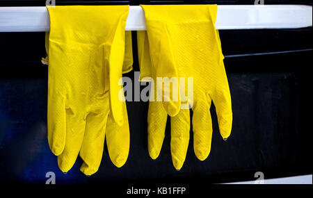 Goma amarilla cocina, lavaplatos, guantes, secado después de utilizar delante de un horno de blanco y negro Foto de stock