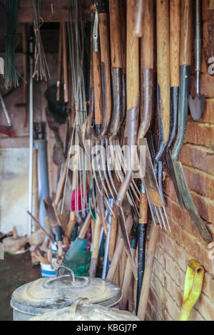 Una colección de herramientas de jardín colgante en un edificio Foto de stock