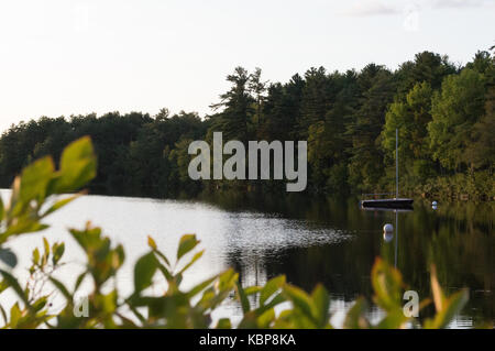 Tarde de otoño se refleja en las aguas del lago nacarada en New Hampshire como el follaje comienza a hacerse aparente Foto de stock
