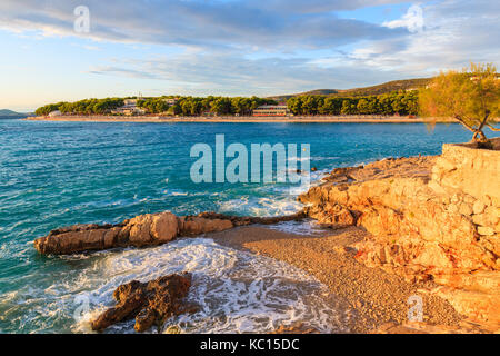 Las olas del mar en la pequeña playa al atardecer en Primosten town, Dalmacia, Croacia Foto de stock