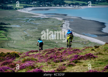 Dos ciclistas de montaña ride un sendero en la colina que domina la bahía de Porlock Bossington en Somerset, Inglaterra.