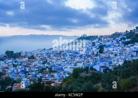 Vista panorámica de la ciudad azul de Chefchaouen en la subida, Marruecos. Nubes sobre cumbres Foto de stock