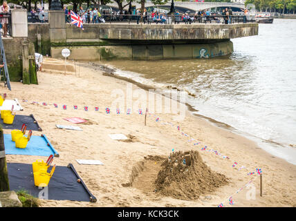Sandcastle, escultura con el escultor buscando donaciones, sobre una playa urbana junto a un ajetreado orilla sur del río Támesis en Londres, Inglaterra, Reino Unido. Foto de stock