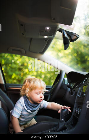 Cute little boy jugando en el coche, pretendiendo para su accionamiento. Foto de stock