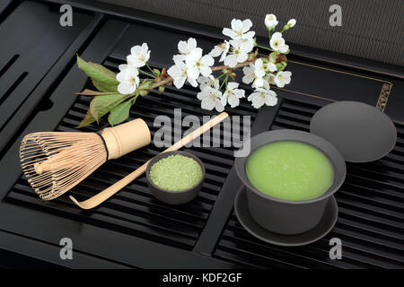 Té verde japonés matcha con polvo y salud beber en taza con batidor, stick agitador y primavera en flor de cerezo negro bandeja.