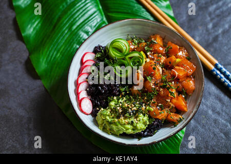 Salmón ahi poke con negro prohibido arroz, encurtido de pepino, aguacate y rábanos Foto de stock