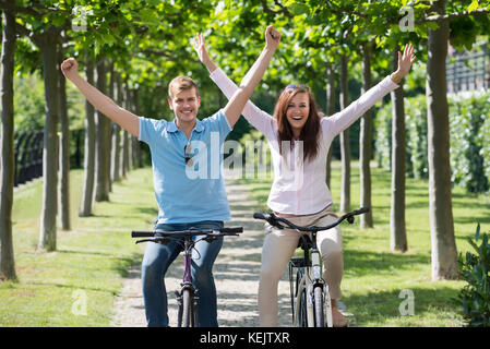 Hombre y mujer divirtiéndose en bicicleta Equitación juntos en el parque Foto de stock