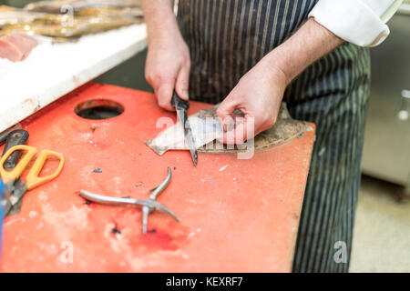 Pescado británico monger filetes de lenguado una y tira de piel lejos en un puesto en el mercado en Yorkshire, Inglaterra, Reino Unido. Foto de stock