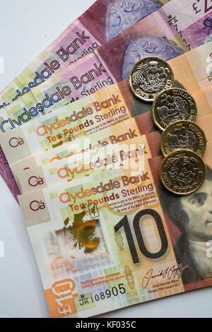 Escocesa Clydesdale Bank 20 20 €, polímero plástico diez billetes de 10 libras con Robert Burns y hexagonal una libra de £1 monedas sobre fondo blanco liso Foto de stock