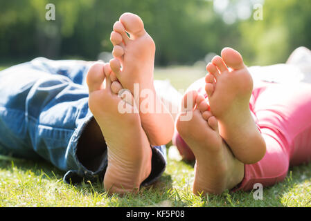 Cerca de dos pies mientras recostados sobre el pasto en park