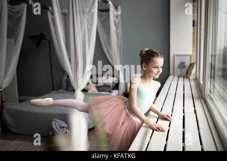 Cute little bailarina de ballet en rosa de traje y zapatos pointe está bailando en la habitación. Niño Niña está estudiando ballet.