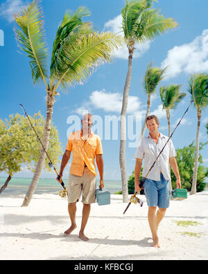 Ee.Uu., Florida, dos hombres caminando en la playa con cañas de pescar y cajas de aparejos, islamorada Foto de stock