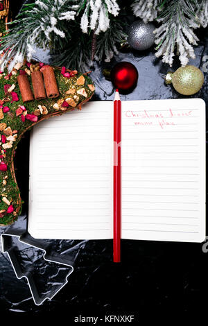 Plan de menús de Navidad. Antecedentes para escribir el menú navideño. Vista desde arriba. Cuaderno sobre fondo negro con decoración