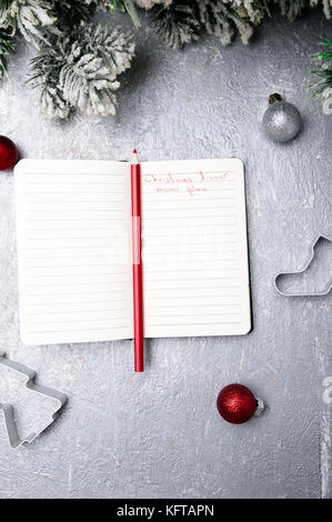 Plan de menús de Navidad. Antecedentes para escribir el menú navideño. Vista desde arriba. Cuaderno sobre fondo gris con decoración