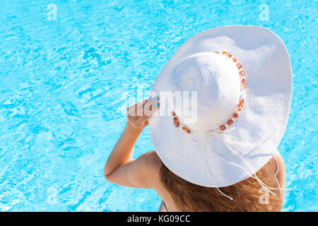 Mujer joven sentada en la cornisa de la piscina Foto de stock