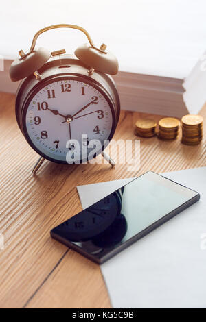 Las horas de trabajo, vintage reloj y teléfono móvil en la oficina de negocios Foto de stock