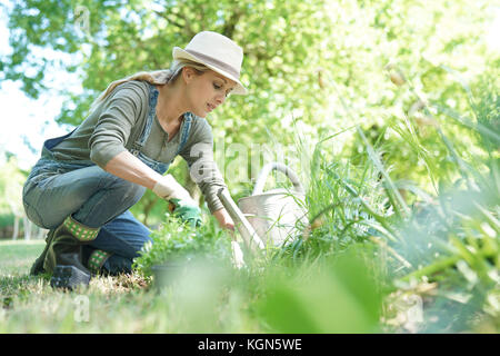 Mujer rubia con sombrero jardinería