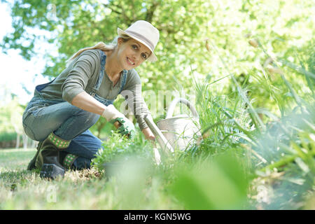 Mujer rubia con sombrero jardinería