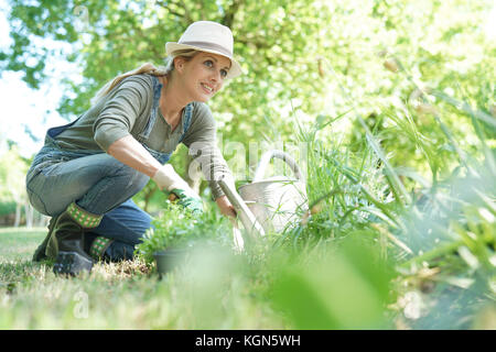 Mujer rubia con sombrero jardinería