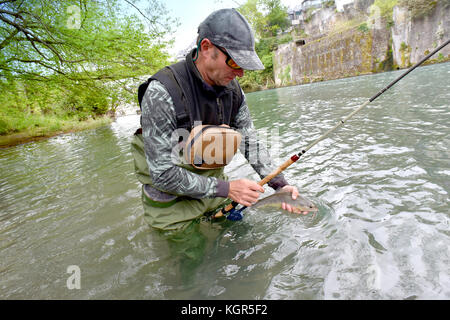 Pescador con mosca celebración fario trucha capturada en el río.
