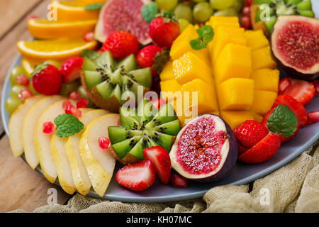 Plato de frutas y bayas. mango, kiwi, higo, uva, fresa, pera y naranja. cocina vegetariana menú dietético. Foto de stock