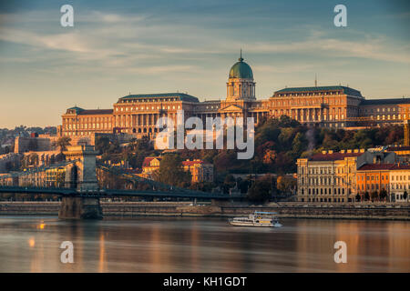 Budapest, Hungría - hermoso amanecer dorado en el lado de Buda con el Palacio Real del Castillo de Buda, el puente de la cadena Szechenyi y barco turístico en el río Danu