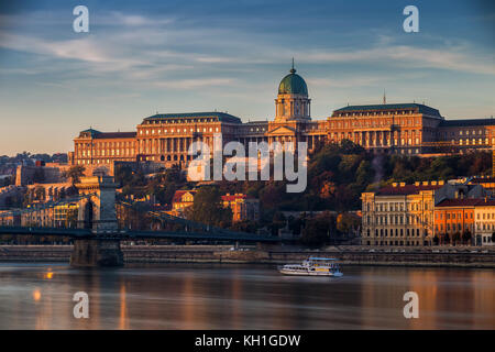 Budapest, Hungría - hermoso amanecer dorado en el lado de Buda con el Palacio Real del Castillo de Buda, el puente de la cadena Szechenyi y barco turístico en el río Danu