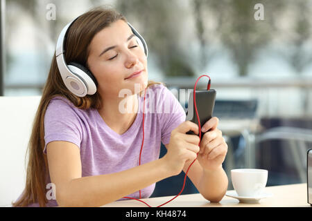 Retrato de una adolescente relajado escuchando música en un bar en la noche