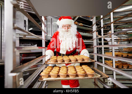 Santa Claus Baker con una bandeja de pastelitos en sus manos sobre Cristo