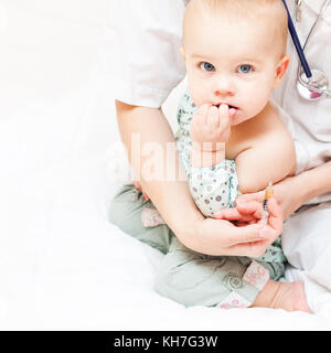 Primer plano de la pediatra, dispuestos a dar una inyección intramuscular de una vacuna a una niña Foto de stock