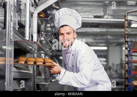 Un hombre panadero con una bandeja de pastelitos.