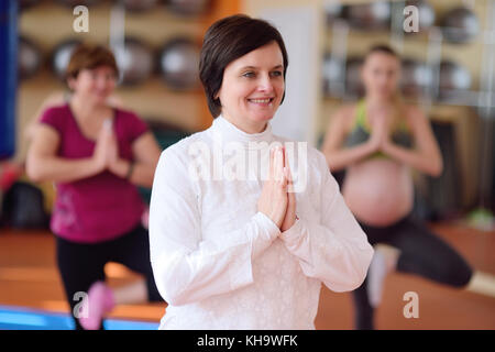 Mujer 40s metida en yoga en el gimnasio estilo de vida activo.