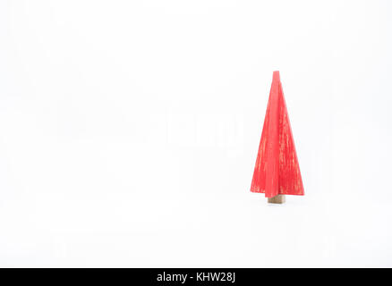 Una estilizada de madera de árbol de Navidad roja con fin apenado contra un fondo blanco. La decoración es a la derecha y la imagen se copia el espacio. Foto de stock