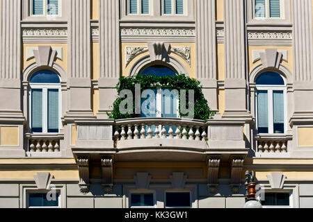 Trieste edificio exterior, fachada y balaustrada balcón con plantas de escalada, en Piazza della Borsa.Trieste, Friuli Venecia Julia, Italia. De cerca. Foto de stock