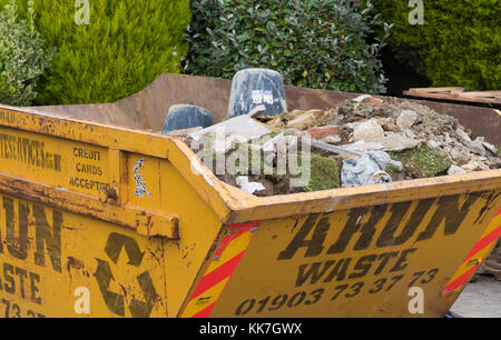 Un salto lleno de escombros y residuos de la construcción en un sitio de construcción privada en el Reino Unido. Foto de stock
