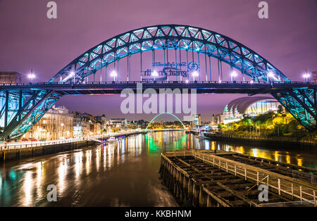 Foto nocturna mirando a lo largo del río Tyne hacia el puente Tyne y el puente Gateshead Millennium, Newcastle upon Tyne, Tyne y Wear, Inglaterra