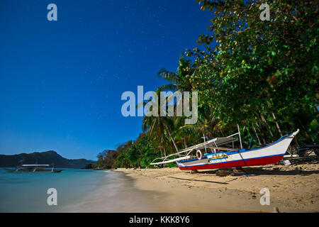 Moonscape en Filipinas con la banca tradicional barco en una playa, con cielo estrellado