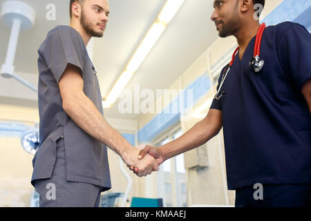 Dos jóvenes médicos un apretón de manos a cada uno de los demás. equipo multirracial de los jóvenes médicos. Foto de stock