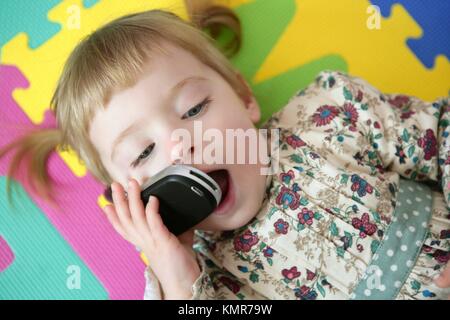 Niño Niña (2,5 años) jugando, hablando por un teléfono de juguete.  Conceptos: el aburrimiento, el cansancio, la imaginación, hacer creer  Fotografía de stock - Alamy