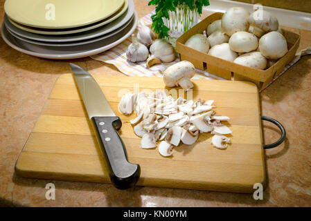 Preparación de "funghi trifolati' (en rodajas finas champignons cocinados con aceite, ajo y perejil) Foto de stock
