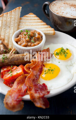 Comida un clásico desayuno inglés completo de huevos bacon o salchichas salchichas frijoles tomates setas y tostadas con café Foto de stock