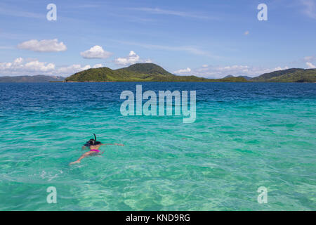 Chica buceando en el agua azul tranquila cerca de pasar Isla,Coron,Filipinas Foto de stock
