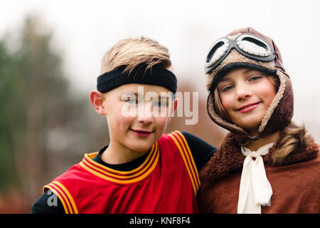 Retrato de niño y hermana gemela vistiendo trajes de piloto y baloncesto para halloween