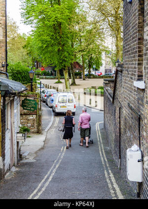 Un par empujando un cochecito de bebé a lo largo del callejón estrecho entre el estanque cuadrado y West Hill, Highgate Village, London, UK, en una tarde de primavera Foto de stock