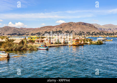 Islas flotantes hechas de totora en el Lago Titicaca, bajo el cielo azul con nubes blancas dispersas Foto de stock