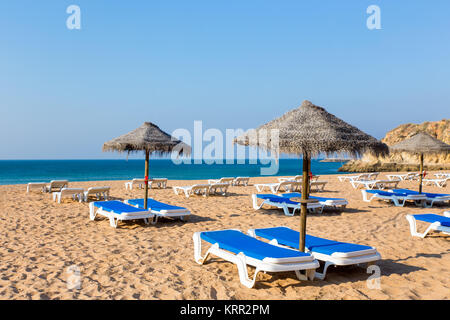 Grupo Playa de mimbre con sombrillas y reposeras de playa azul Foto de stock