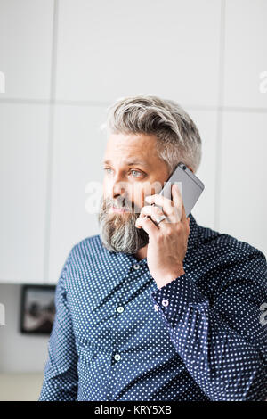 Un hombre en una camisa manchada hablando por un teléfono celular Foto de stock