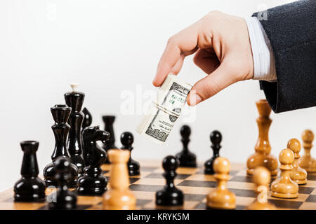 Hombre de negocios mano sujetando la moneda dólar injusto juego de ajedrez Foto de stock